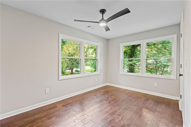 spare room with dark wood-style floors, visible vents, ceiling fan, and baseboards