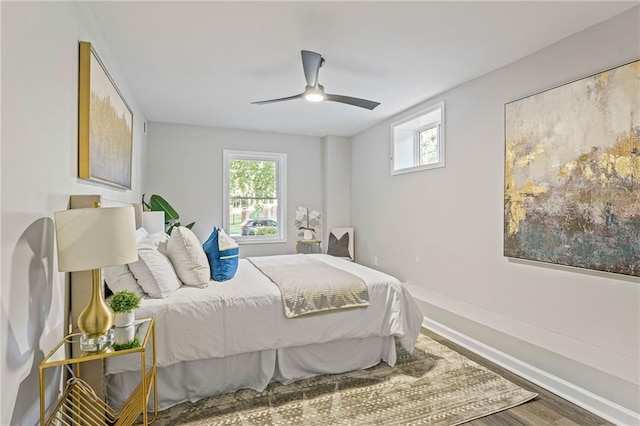 bedroom featuring ceiling fan, multiple windows, wood finished floors, and baseboards