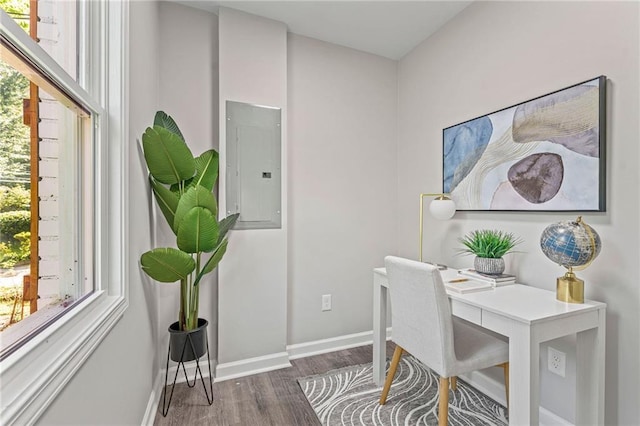 office area with dark wood-style flooring, electric panel, and baseboards