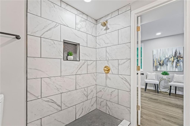 bathroom featuring tiled shower, wood finished floors, toilet, and baseboards