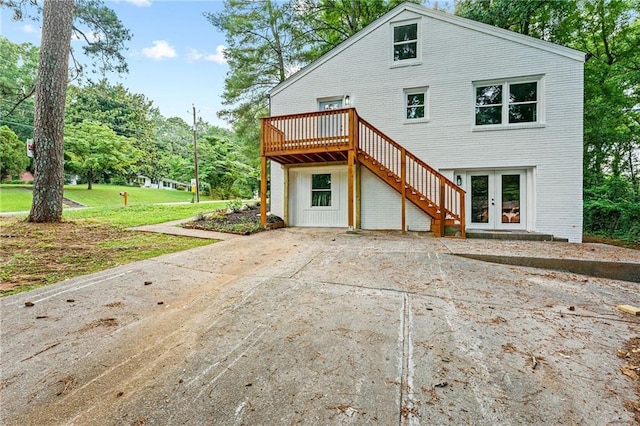 rear view of house featuring a deck, a yard, french doors, and stairway