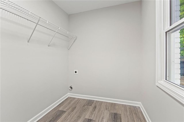 laundry area featuring laundry area, baseboards, hookup for an electric dryer, and wood finished floors