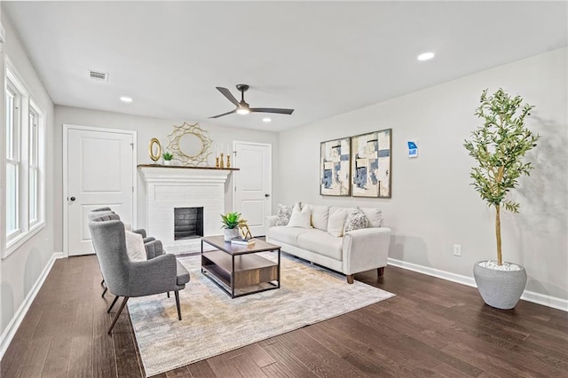 living room with baseboards, visible vents, dark wood-type flooring, a fireplace, and recessed lighting