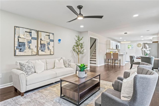 living area with baseboards, stairway, wood finished floors, and recessed lighting