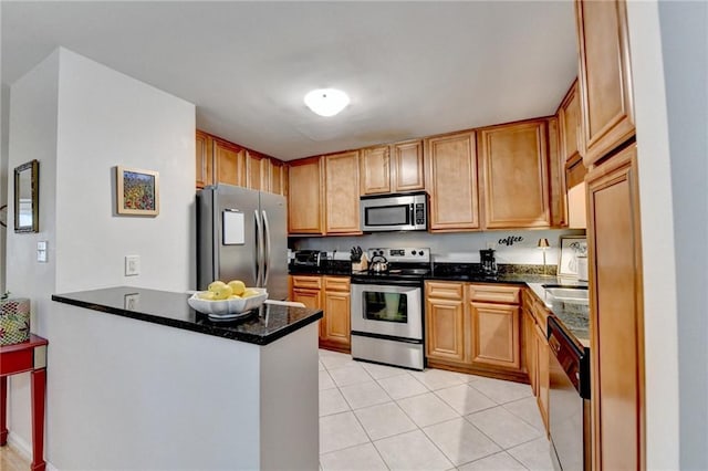 kitchen with light tile patterned floors, dark stone counters, kitchen peninsula, and appliances with stainless steel finishes