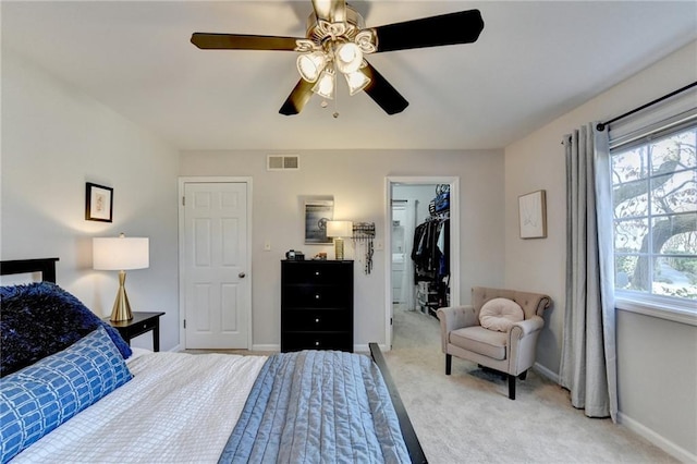 carpeted bedroom with a spacious closet, ceiling fan, and a closet