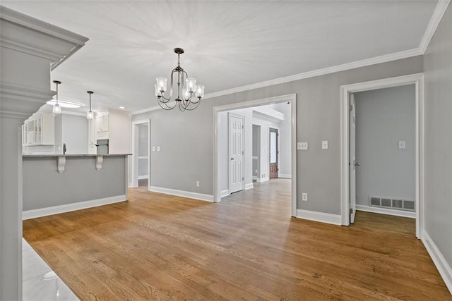 unfurnished dining area featuring light hardwood / wood-style flooring, crown molding, and a notable chandelier