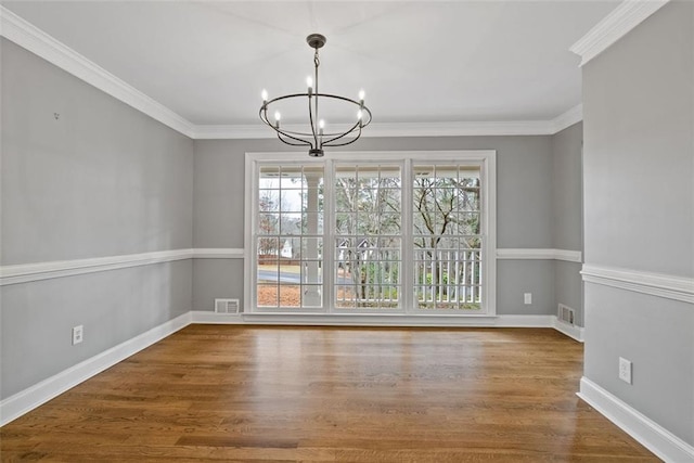 unfurnished dining area featuring hardwood / wood-style floors, a chandelier, and ornamental molding