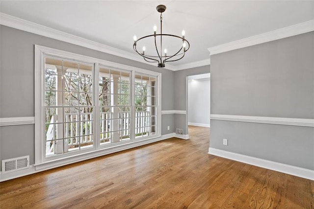 unfurnished dining area featuring hardwood / wood-style floors, ornamental molding, and a notable chandelier