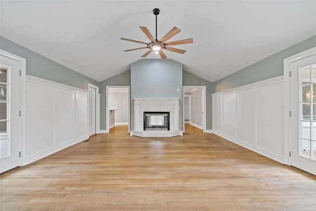 unfurnished living room featuring ceiling fan, light hardwood / wood-style floors, lofted ceiling, and a fireplace