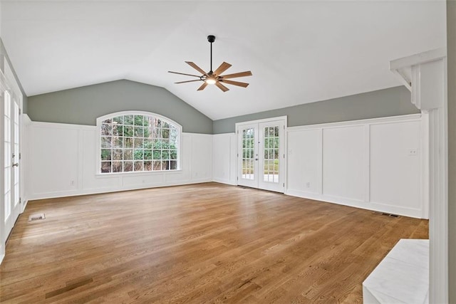 unfurnished living room featuring ceiling fan, light hardwood / wood-style floors, vaulted ceiling, and french doors