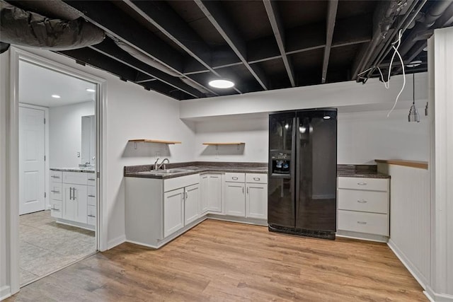 kitchen featuring black fridge with ice dispenser, white cabinets, light hardwood / wood-style floors, and sink