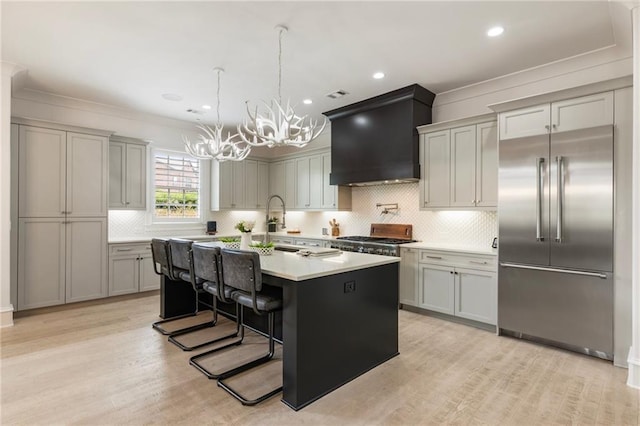 132 Grand Cres, Alpharetta, GA 30009 - kitchen with appliances with stainless steel finishes, wall chimney exhaust hood, a chandelier, an island with sink, and light countertops