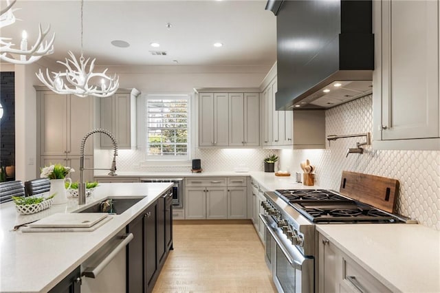 132 Grand Cres, Alpharetta, GA 30009 - kitchen with appliances with stainless steel finishes, wall chimney range hood, light countertops, light wood-style floors, and hanging light fixtures