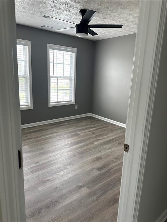 unfurnished room featuring wood-type flooring, ceiling fan, and a textured ceiling