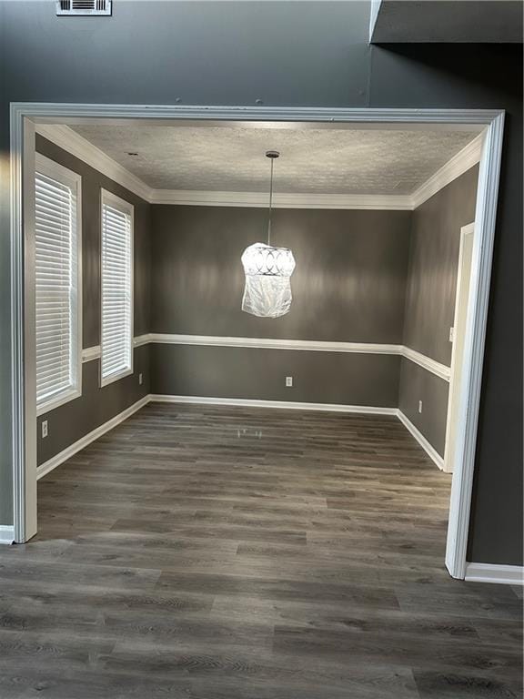 unfurnished dining area with crown molding, an inviting chandelier, and dark wood-type flooring