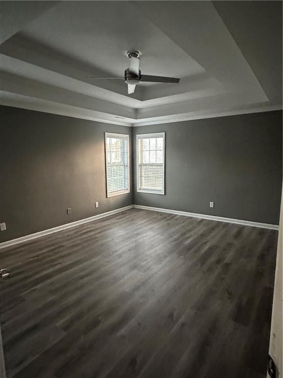 unfurnished room featuring crown molding, ceiling fan, a tray ceiling, and dark hardwood / wood-style flooring