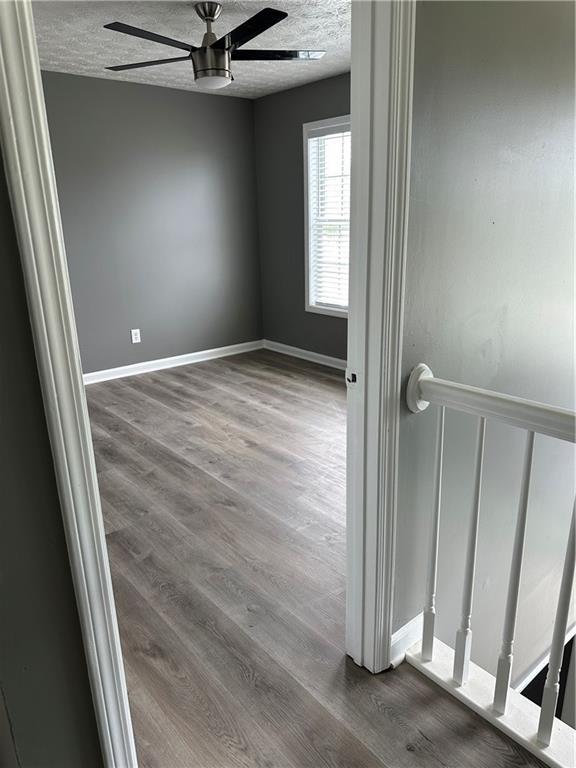 empty room featuring ceiling fan, hardwood / wood-style floors, and a textured ceiling