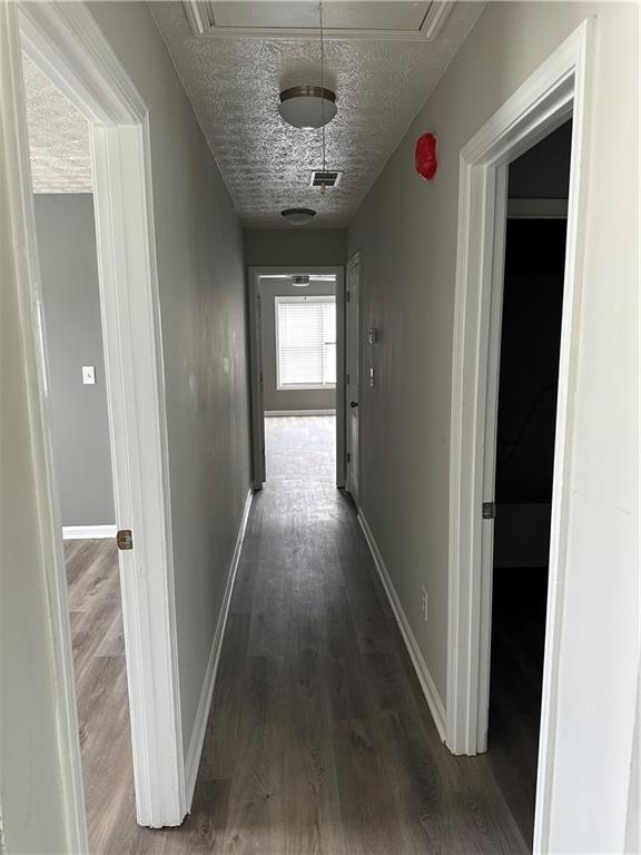 hall featuring dark wood-type flooring and a textured ceiling