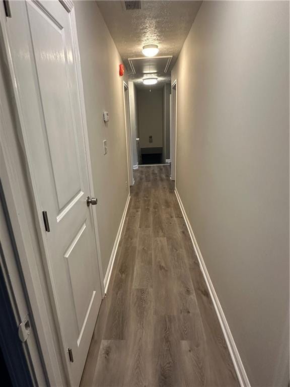 hallway with dark wood-type flooring and a textured ceiling