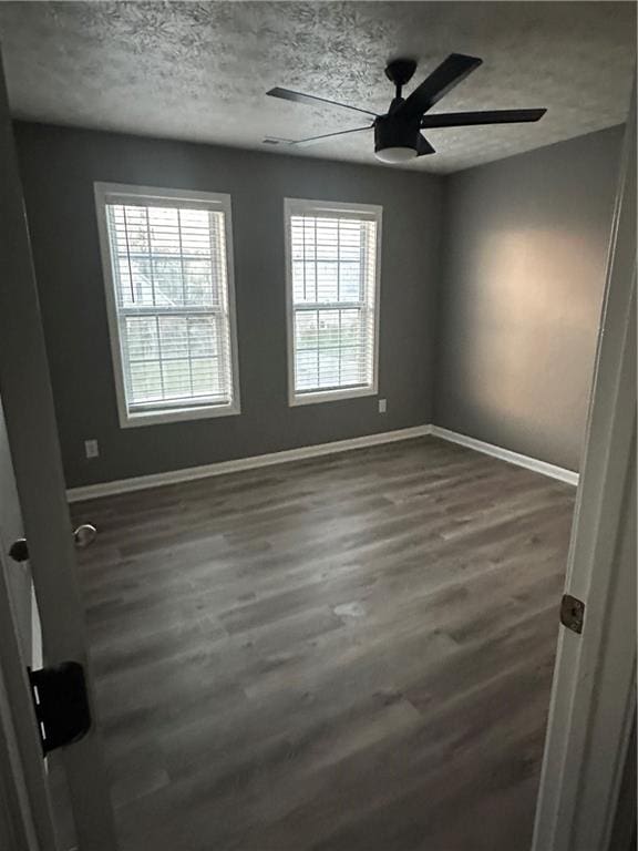 unfurnished room with ceiling fan, dark wood-type flooring, and a textured ceiling