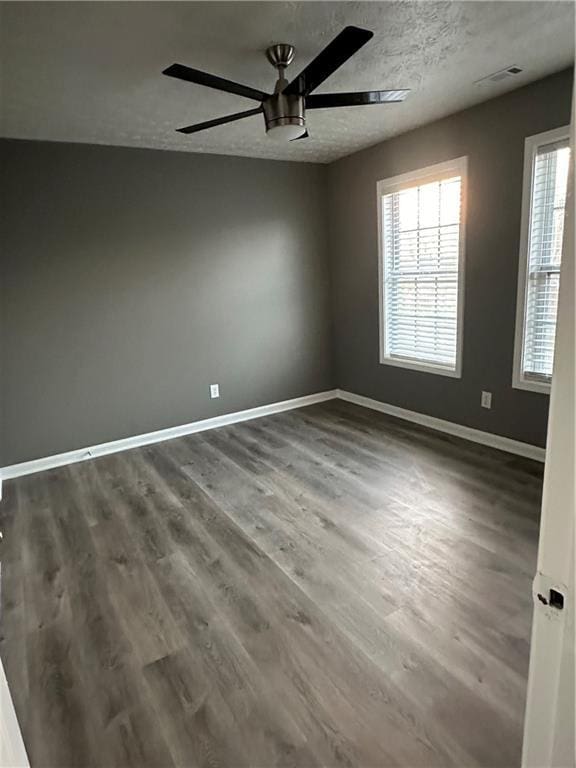 spare room with a textured ceiling, dark hardwood / wood-style floors, and ceiling fan