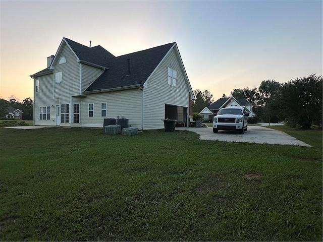 exterior space with a garage, central air condition unit, and a lawn