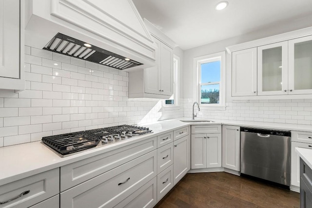 kitchen with white cabinets, glass insert cabinets, appliances with stainless steel finishes, custom exhaust hood, and light countertops