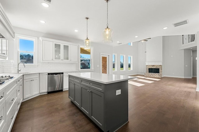 kitchen with stainless steel appliances, a kitchen island, visible vents, white cabinets, and light countertops