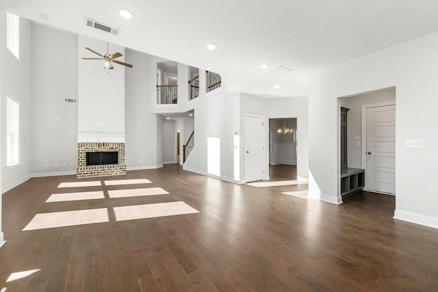 unfurnished living room with a fireplace, visible vents, dark wood-type flooring, baseboards, and stairs