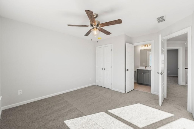 unfurnished bedroom featuring light carpet, visible vents, baseboards, a closet, and ensuite bath