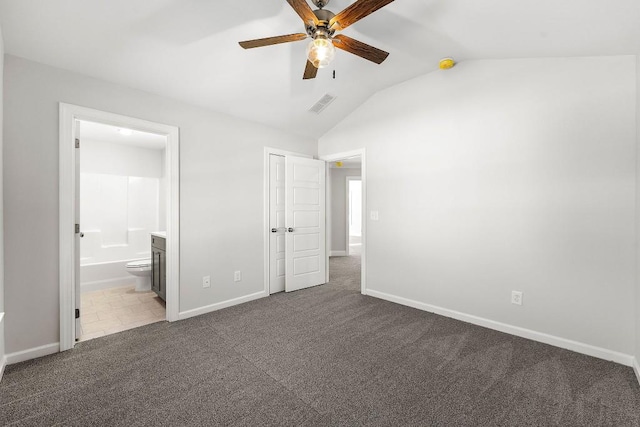 unfurnished bedroom with lofted ceiling, carpet floors, visible vents, baseboards, and ensuite bath