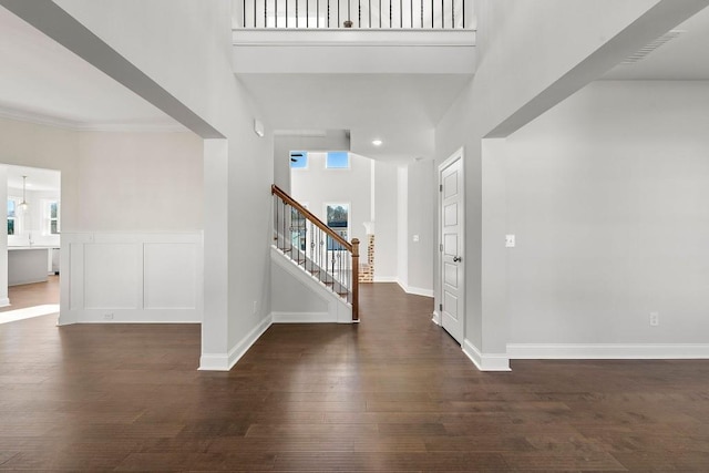 entryway featuring dark wood finished floors, stairway, a high ceiling, ornamental molding, and baseboards