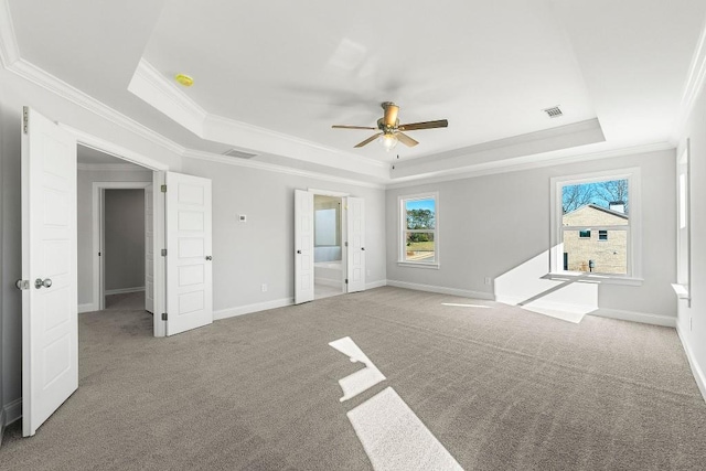 unfurnished bedroom with carpet floors, a tray ceiling, and multiple windows