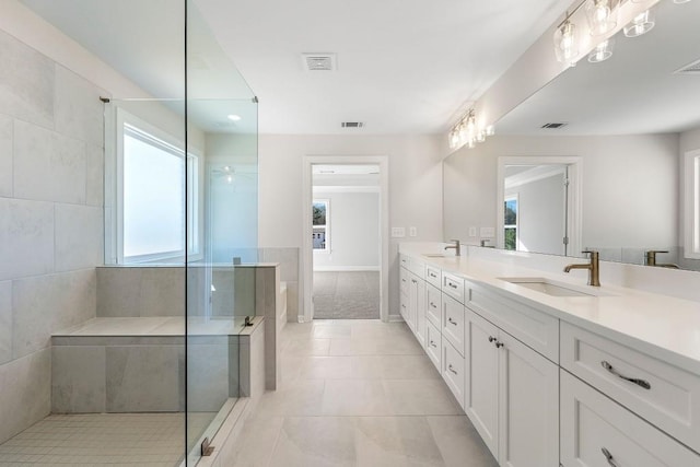 bathroom featuring double vanity, visible vents, a sink, a walk in shower, and tile patterned flooring