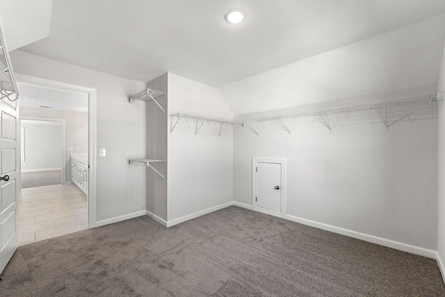 spacious closet featuring vaulted ceiling, carpet floors, and tile patterned floors