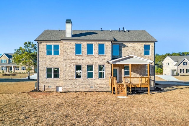 back of house with brick siding, a shingled roof, a yard, crawl space, and a chimney