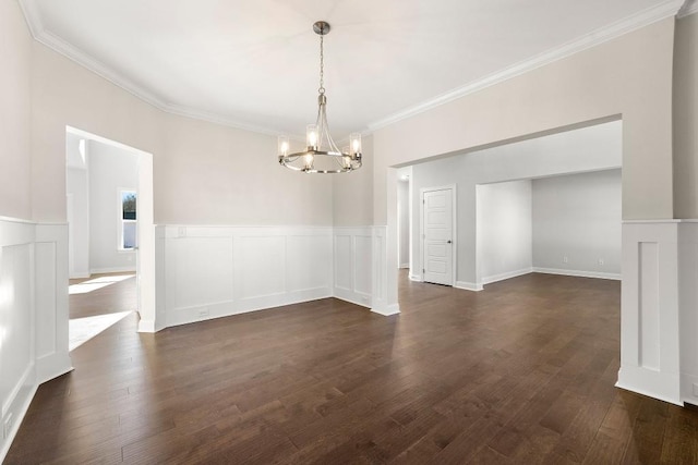 unfurnished dining area featuring a wainscoted wall, ornamental molding, dark wood-style flooring, a decorative wall, and a notable chandelier