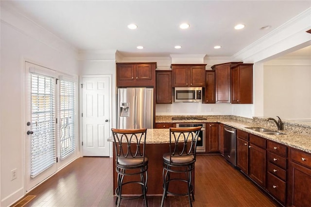 kitchen with sink, dark hardwood / wood-style floors, a kitchen bar, appliances with stainless steel finishes, and ornamental molding