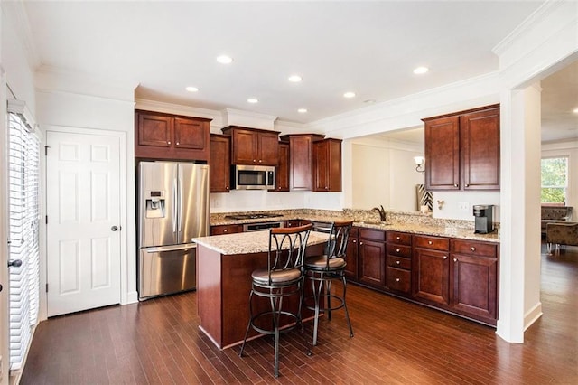 kitchen featuring dark wood-type flooring, a kitchen breakfast bar, sink, kitchen peninsula, and stainless steel appliances