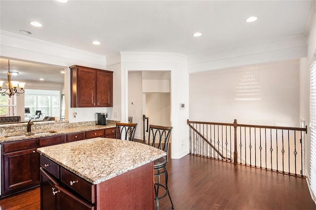 kitchen with a center island, sink, dark hardwood / wood-style floors, ornamental molding, and a chandelier