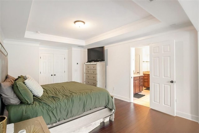 bedroom featuring ornamental molding, a raised ceiling, hardwood / wood-style flooring, connected bathroom, and a closet