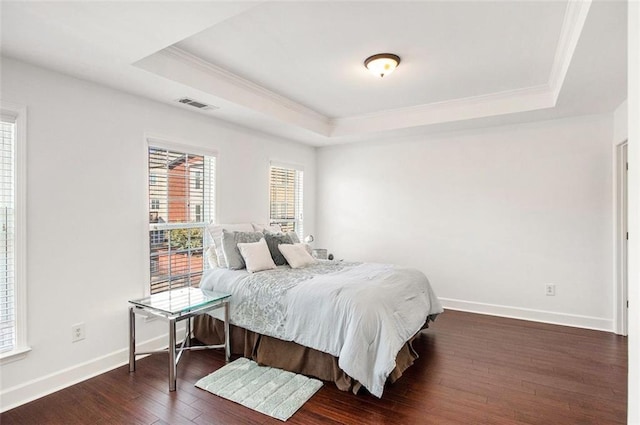 bedroom featuring a tray ceiling, crown molding, and dark wood-type flooring