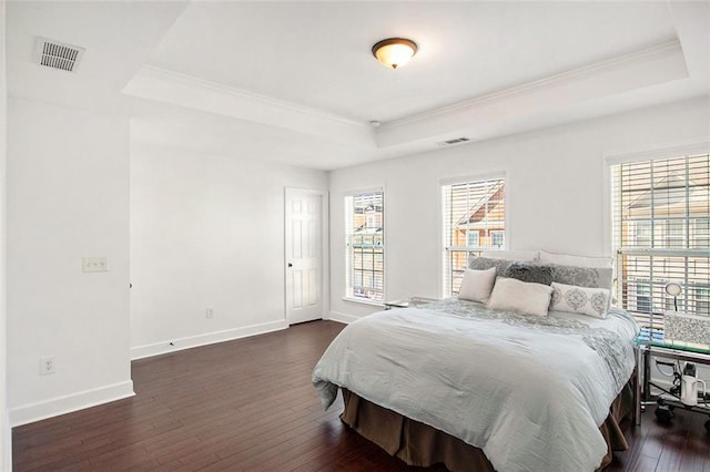 bedroom featuring a raised ceiling, dark wood-type flooring, and ornamental molding