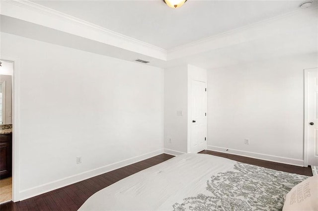 bedroom featuring ornamental molding, dark wood-type flooring, and connected bathroom