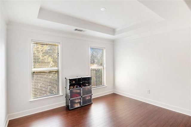 spare room featuring dark hardwood / wood-style floors, ornamental molding, and a tray ceiling