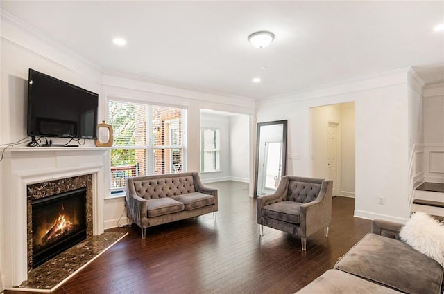 living room with dark hardwood / wood-style flooring, crown molding, and a premium fireplace