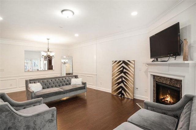 living room with a fireplace, ornamental molding, an inviting chandelier, and dark wood-type flooring