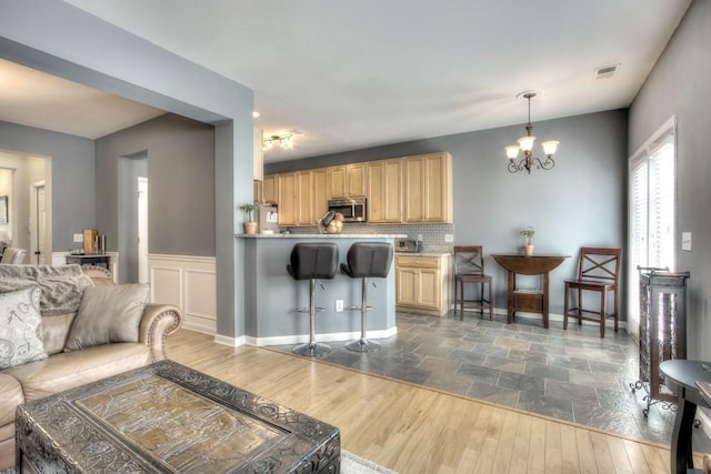 living room with dark wood-type flooring, a wainscoted wall, visible vents, and a notable chandelier