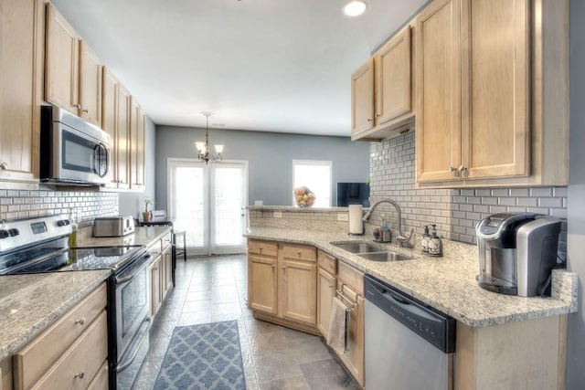 kitchen with light brown cabinetry, appliances with stainless steel finishes, light stone counters, a chandelier, and sink